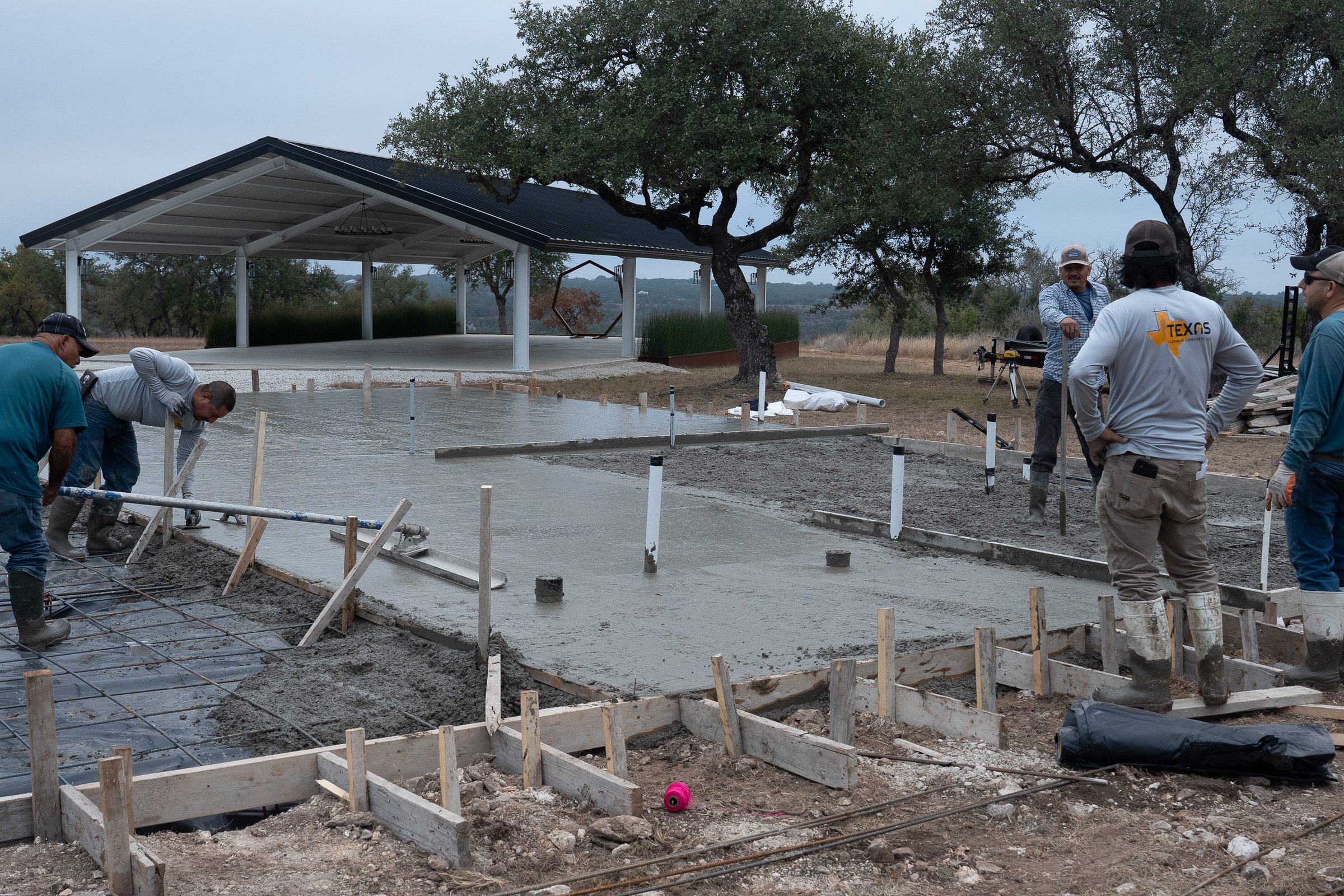 Crew finishing a wide pad beside the pavilion