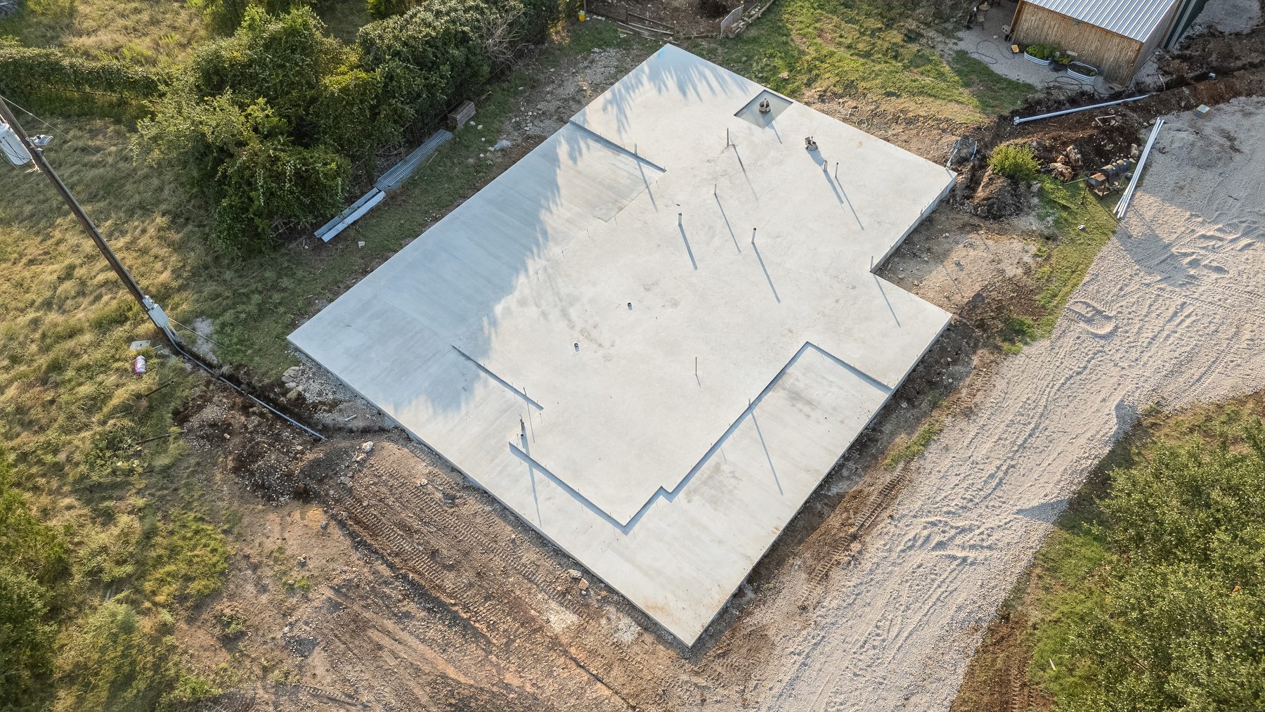 Aerial view of a wide new slab foundation surrounded by oak trees
